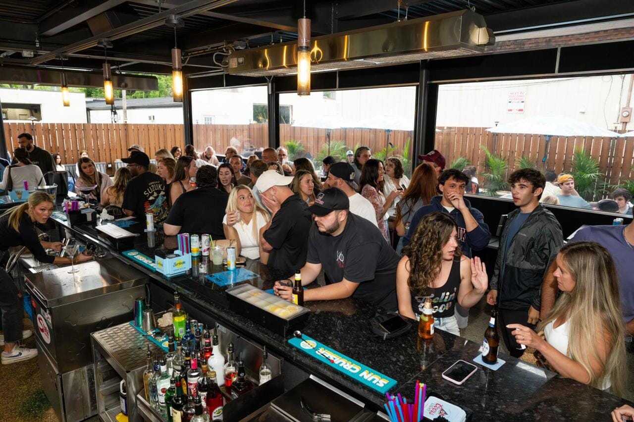 Crowded patio bar at Erie + Vine in downtown Willoughby, Ohio, with guests socializing, enjoying drinks, and creating a lively summer nightlife atmosphere.